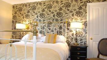 A neatly made bed with a headboard, a bedside table with a lamp, and a chair.