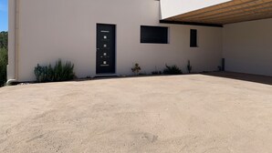 A modern building with a minimalist design, featuring a black door, a small window, and a concrete driveway. - Jolie Dépendance Avec sa Très Belle vue mer (Pietrosella)