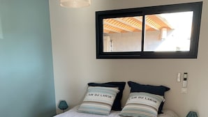 A bedroom with a bed, two bedside tables, a window, and a hanging light fixture. - Jolie Dépendance Avec sa Très Belle vue mer (Pietrosella)