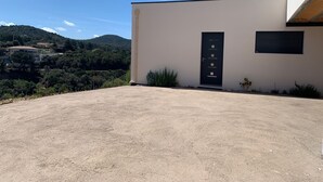 A modern building with a black door and a small window, surrounded by a gravel driveway and greenery. - Jolie Dépendance Avec sa Très Belle vue mer (Pietrosella)