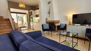 Ein Wohnzimmer mit einer Couch, zwei Sesseln, einem Couchtisch, einem Fernseher und einem Kamin.