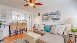 A modern living room with a sofa, ottoman, and a ceiling fan. - Driftwood Getaway! South Mission Beach (San Diego)