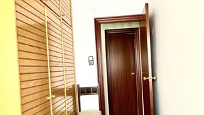 Un couloir avec une armoire en bois, un banc et une porte.