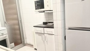 Une cuisine avec des meubles blancs, un four à micro-ondes et un réfrigérateur.