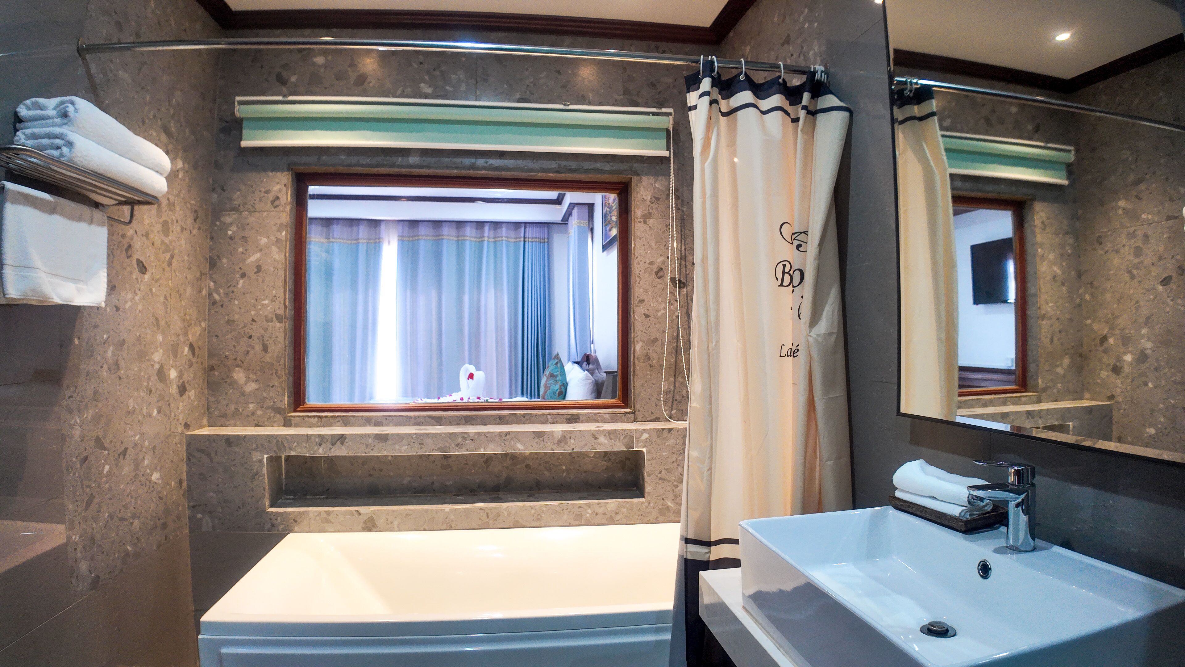 Ein Badezimmer mit großem Fenster, einer Badewanne, einem Waschbecken und einem Spiegel.