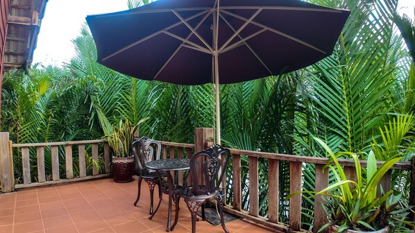 Un patio al aire libre con una mesa y sillas, rodeado de abundante follaje.