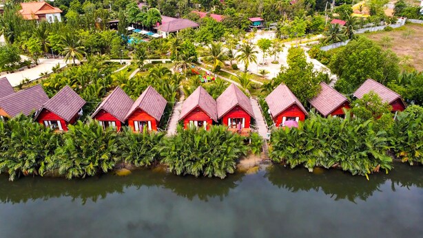 A row of red-roofed cottages with a water body in the foreground. - Lodge Moni Essara Kompot (Kampot)