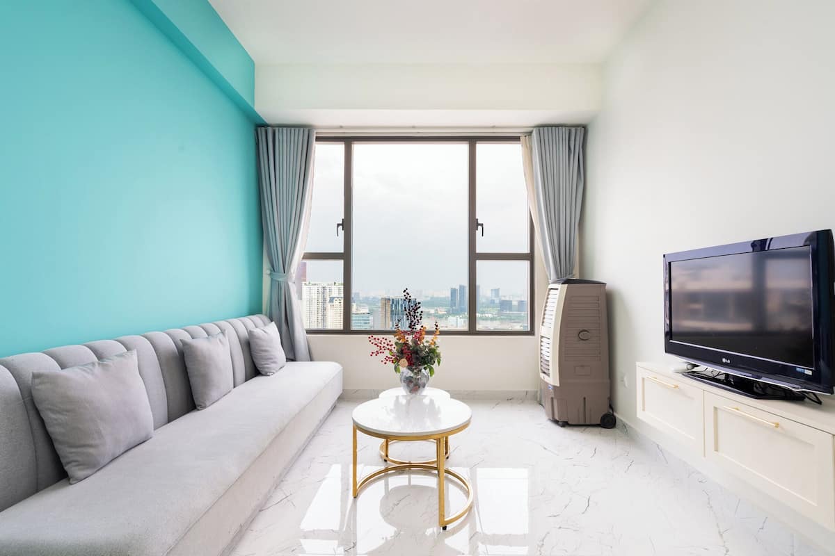 A modern living room with a sofa, a coffee table, a TV, and a view of the city.