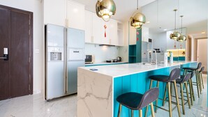 A modern kitchen with a marble island, stainless steel appliances, and a teal accent wall. - RIVERGATE apartment infinity pool & Gym  (Ho Chi Minh City)