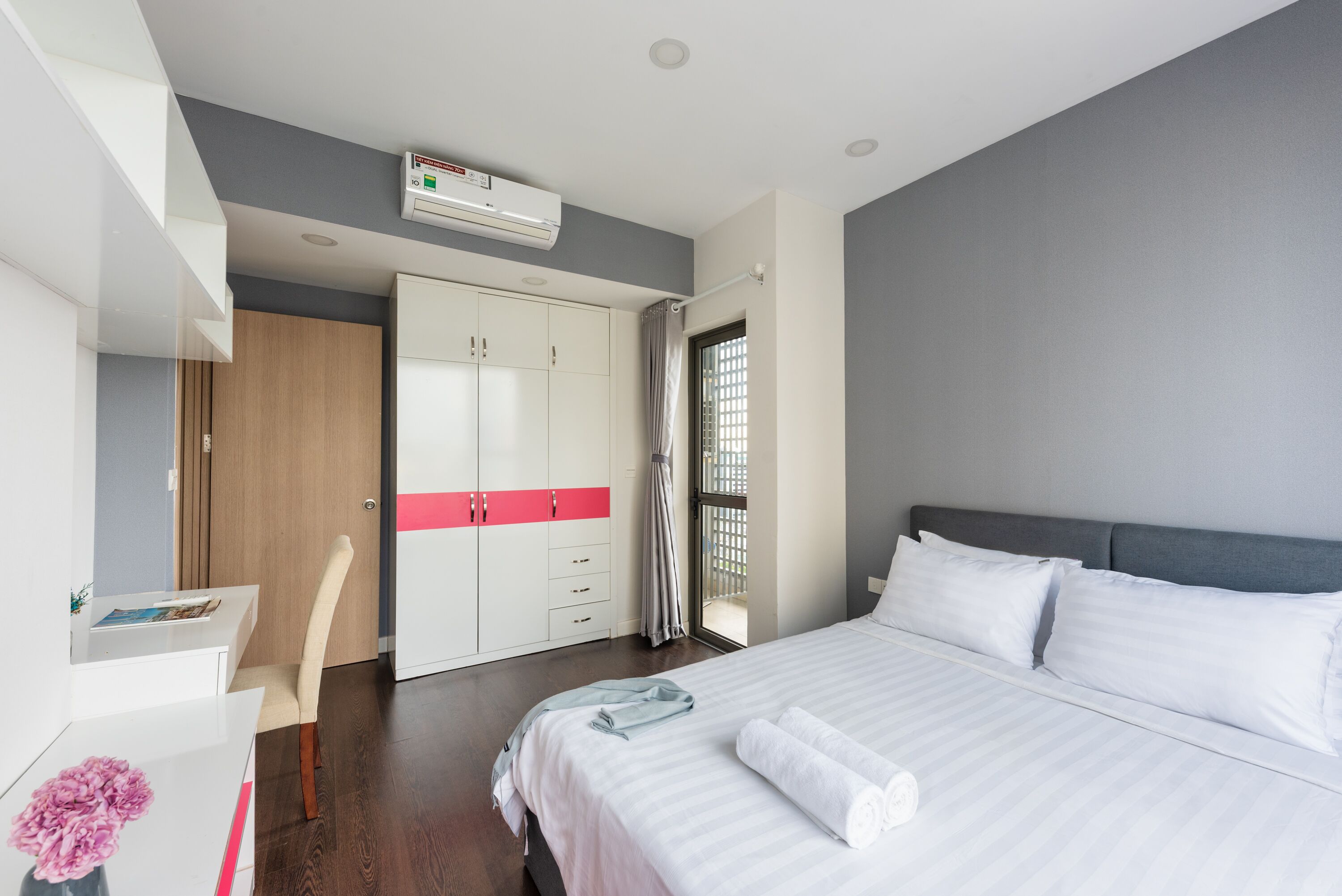 A modern hotel room with a large bed, a desk, and a wardrobe.