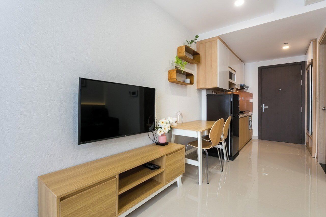 A modern kitchen with a flat-screen TV, wooden cabinets, and a dining area with a table and chairs.