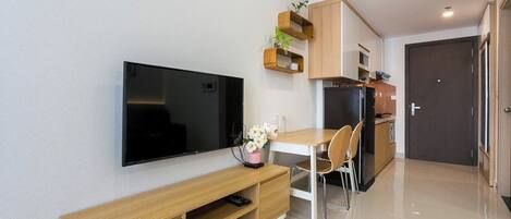 A modern kitchen with a flat-screen TV, wooden cabinets, and a dining area with a table and chairs.