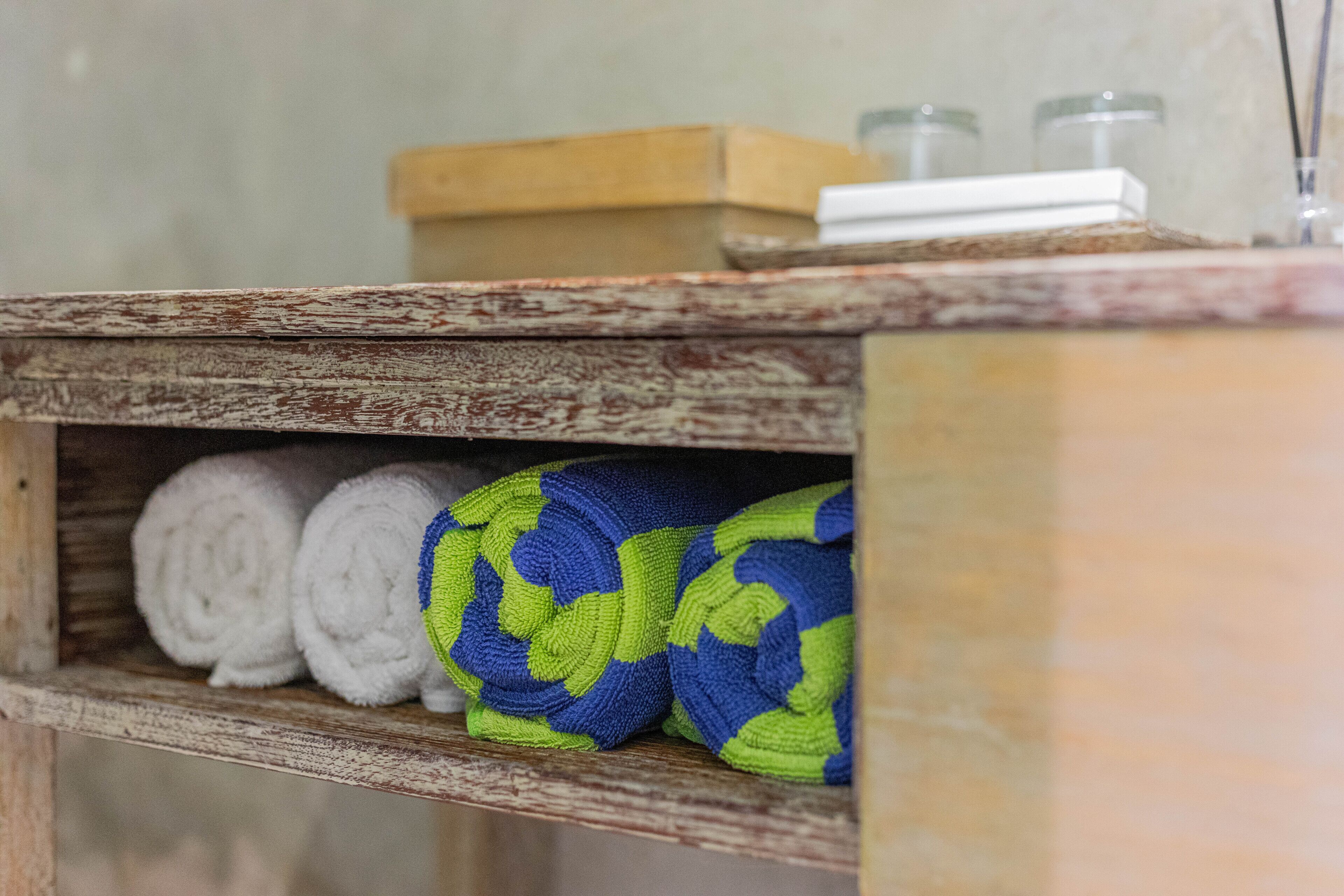 A wooden shelf with rolled towels and a soap dish.