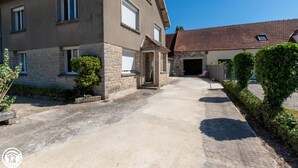 A two-story house with a stone facade, a garage, and a paved driveway. - La Maison de Fabrice (Vauchamps)