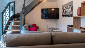 Una sala de estar moderna con una escalera, un televisor de pantalla plana y un cuadro en la pared.