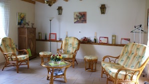 A room with wicker furniture, a wooden cabinet, and wall-mounted decorations. - Les Trelles - Pleurs (Pleurs)