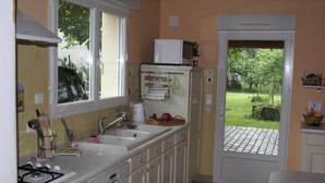 A compact kitchen with a gas stove, sink, and a microwave on the countertop. - Les Trelles - Pleurs (Pleurs)