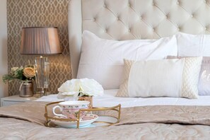 A neatly made bed with a tufted headboard, a bedside lamp, a vase with flowers, and a tray with a teacup and saucer. - Manchester - House - (Manchester)