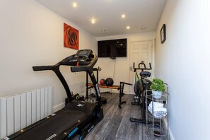A home gym with a treadmill, stationary bike, and weight bench. - Manchester - House - (Manchester)