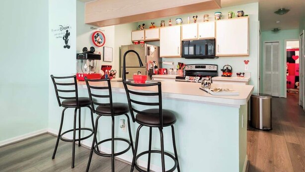 A modern kitchen with a central island, bar stools, a coffee machine, and a microwave. - Disney, Pool, Hot Tub, Gym! (Kissimmee)