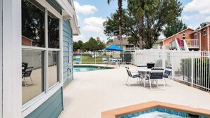A pool area with a hot tub, lounge chairs, and a fenced patio. - Disney, Pool, Hot Tub, Gym! (Kissimmee)