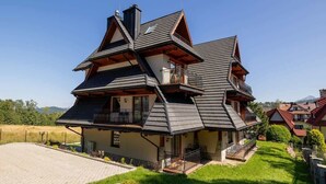 A multi-story house with a sloped roof, a balcony on the second floor, and a small front porch.