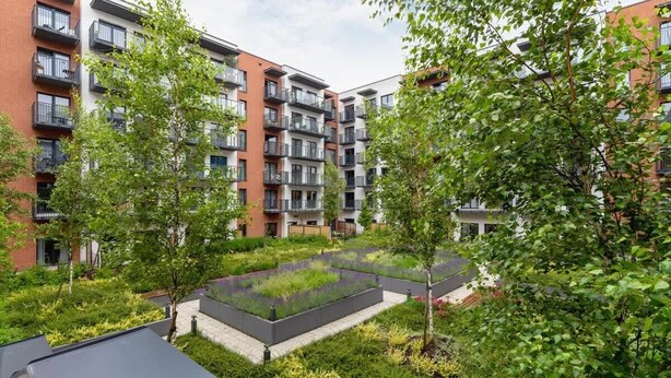 Un immeuble d’appartements moderne doté de nombreux balcons, d’un jardin sur le toit et d’une végétation luxuriante.