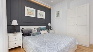 Un dormitorio con una cama grande, dos mesitas de noche, un armario y obras de arte en las paredes.
