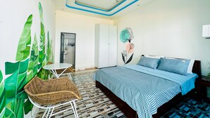 A modern bedroom with a bed, a small table, and chairs. There is a bathroom visible through an open door. - Ben's House 3 (Da Nang)
