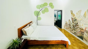 A bedroom with a bed, a wall-mounted plant, and a door leading to a bathroom. - Ben's House 3 (Da Nang)