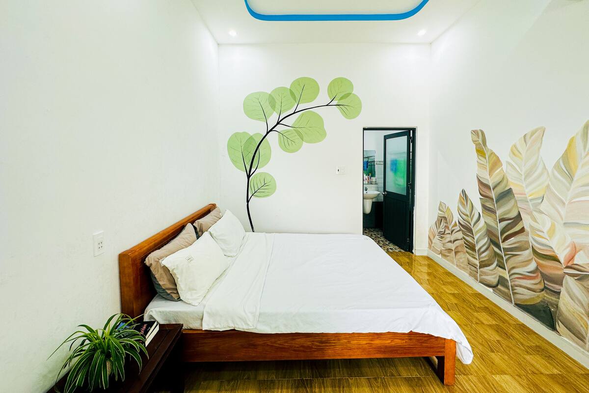 A bedroom with a bed, a wall-mounted plant, and a door leading to a bathroom.