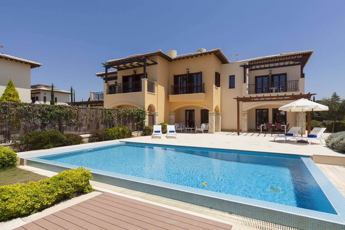 A two-story house with a swimming pool, outdoor seating, and a well-maintained garden.
