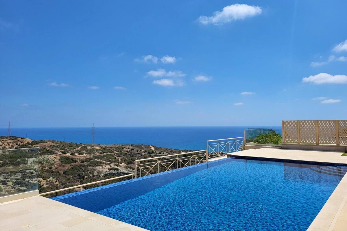 A clear blue sky, a swimming pool, and a view of the sea.