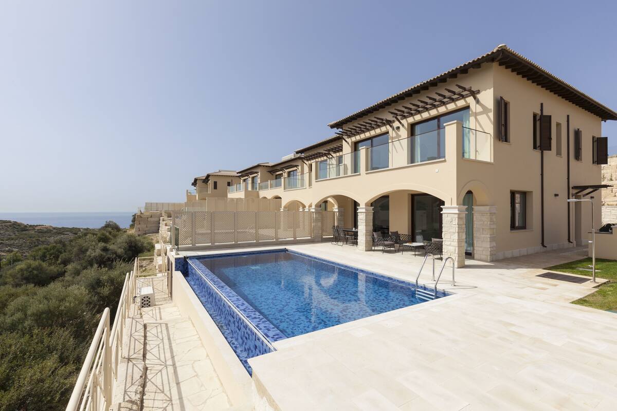 A modern house with a swimming pool, outdoor seating, and a view of the landscape.