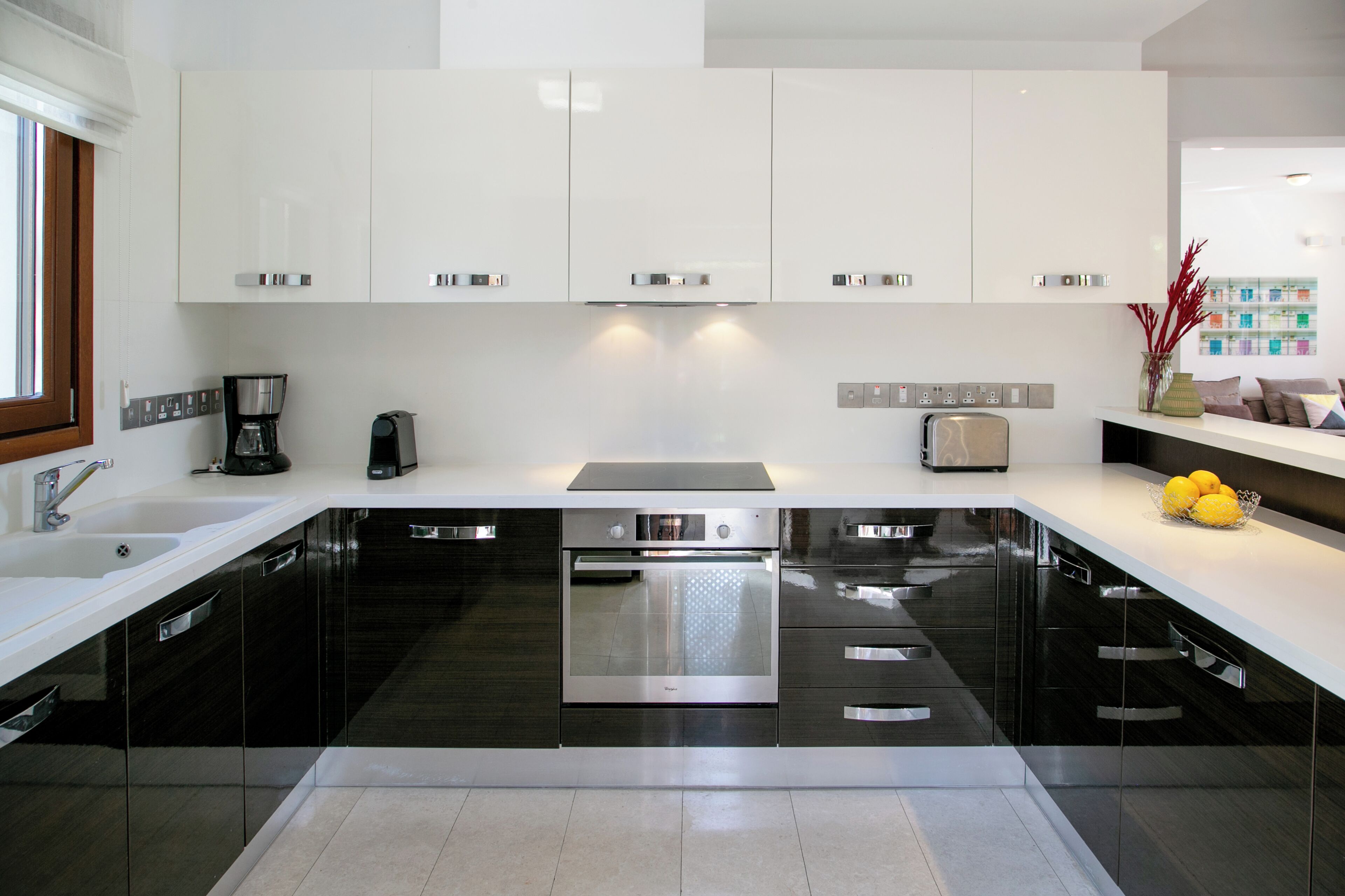 A modern kitchen with black cabinets, stainless steel appliances, and a white countertop.