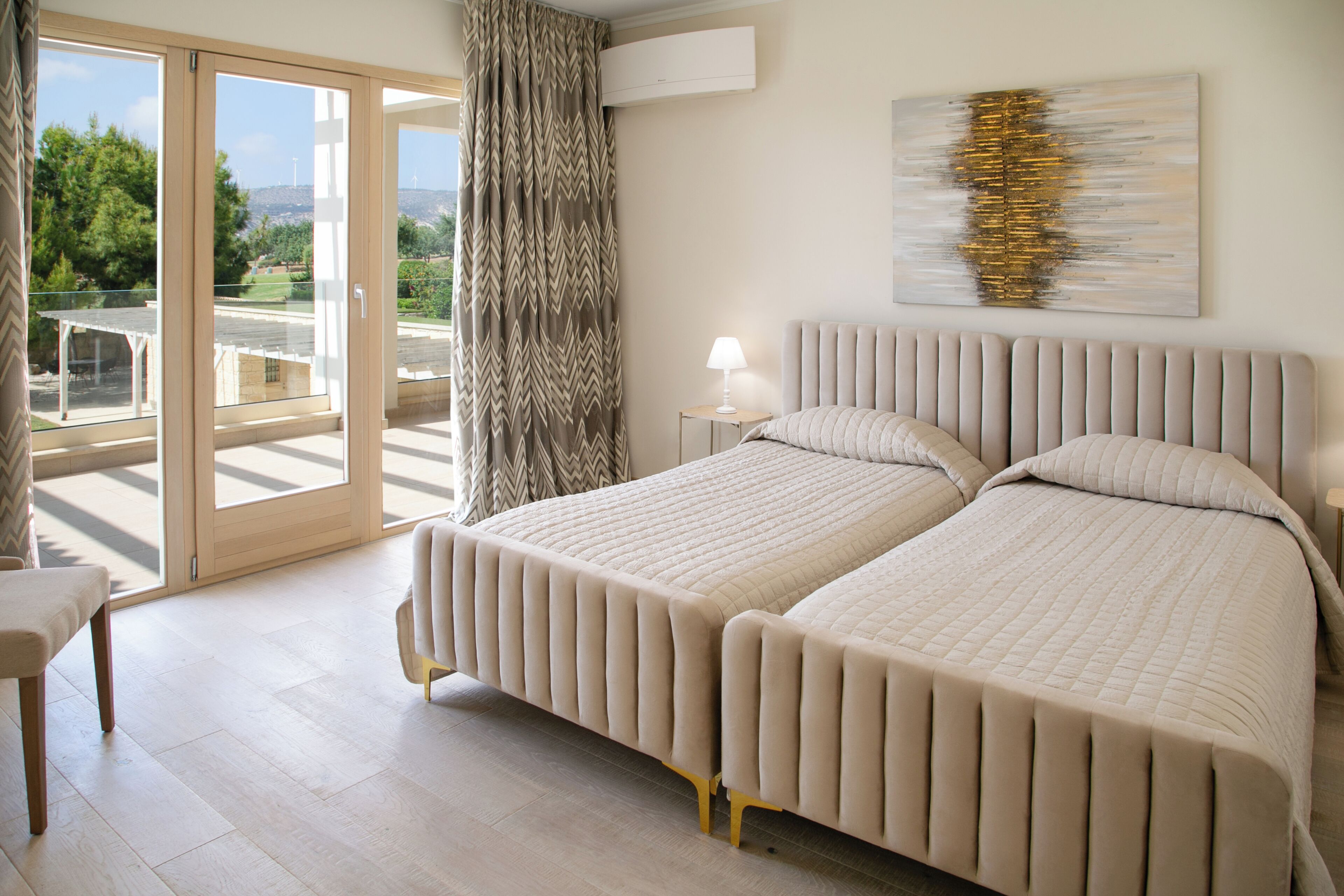 Un dormitorio con dos camas, vistas al exterior y un cuadro abstracto moderno en la pared.