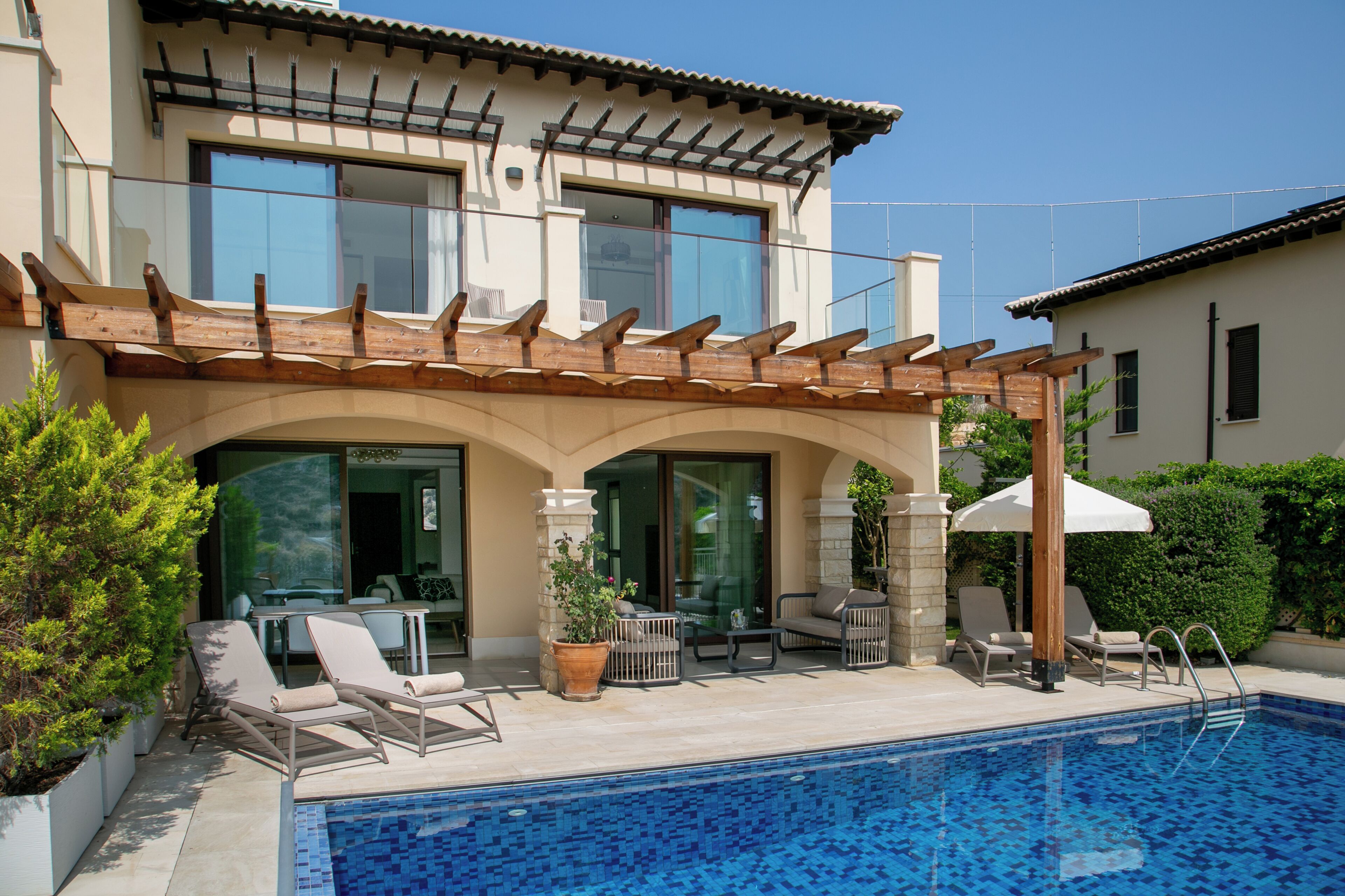 Una casa moderna con piscina, area relax esterna e un pergolato.