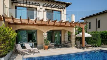 Una casa moderna con piscina, area relax esterna e un pergolato.