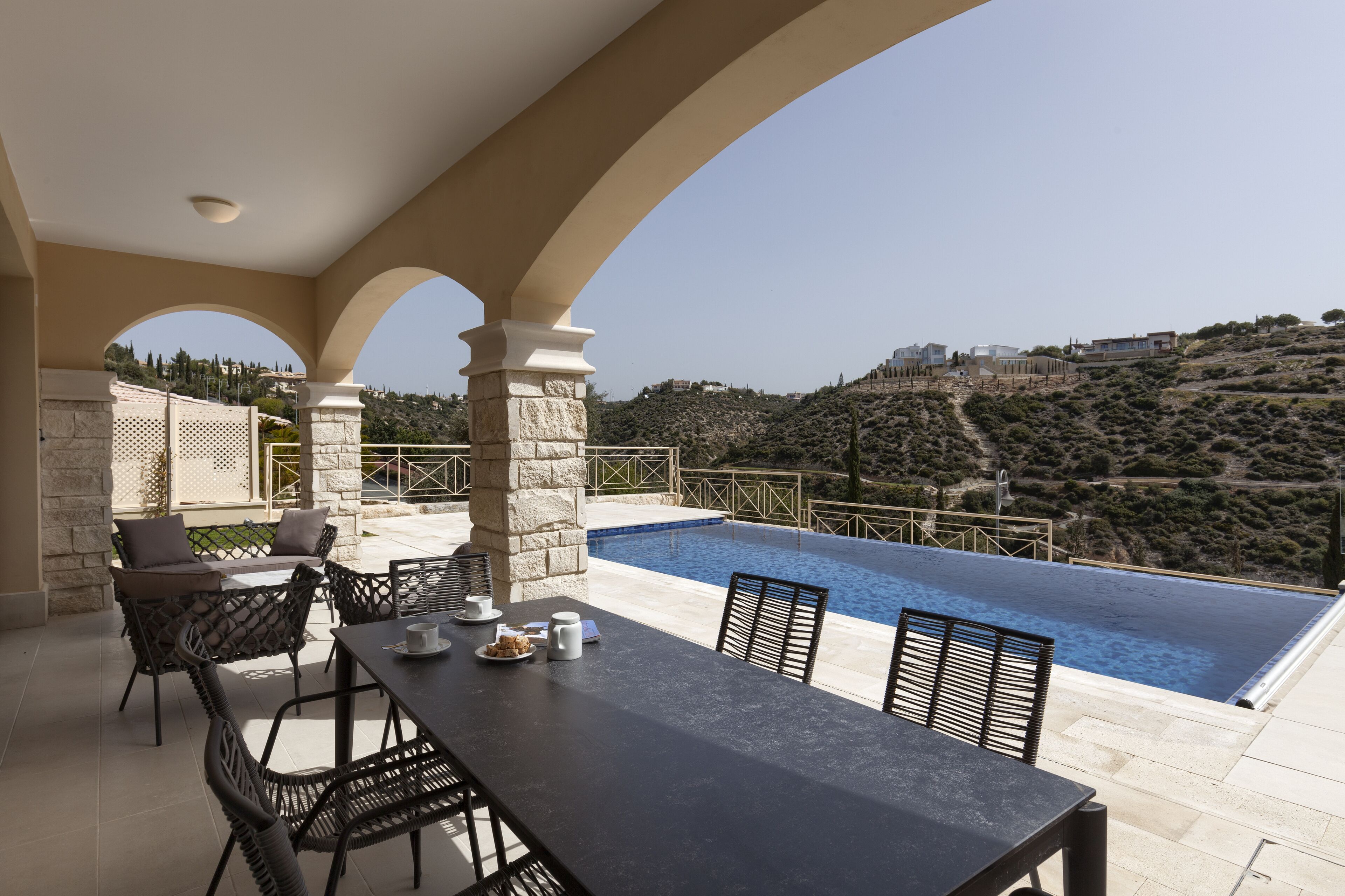 A rooftop terrace with a pool, stone pillars, and outdoor furniture.