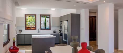Une cuisine moderne avec un îlot central, des meubles gris et une grande fenêtre.