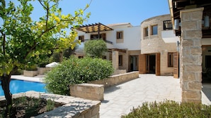 A courtyard with a swimming pool, stone walls, and a variety of plants.