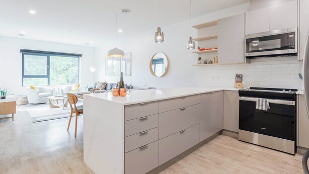 A modern kitchen with a central island, stainless steel appliances, and a dining area with a sofa and chairs. - Le Refuge - Revelstoke Condo with Hot Tub (Revelstoke)