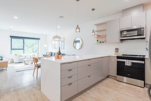 A modern kitchen with a central island, stainless steel appliances, and a dining area with a sofa and chairs.