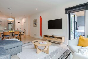 Un salon moderne comprenant un canapé, une table basse, un téléviseur et un coin repas avec des chaises et une table.