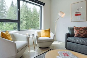 A modern living room with two sofas, a floor lamp, and a coffee table. - Le Refuge - Revelstoke Condo with Hot Tub (Revelstoke)