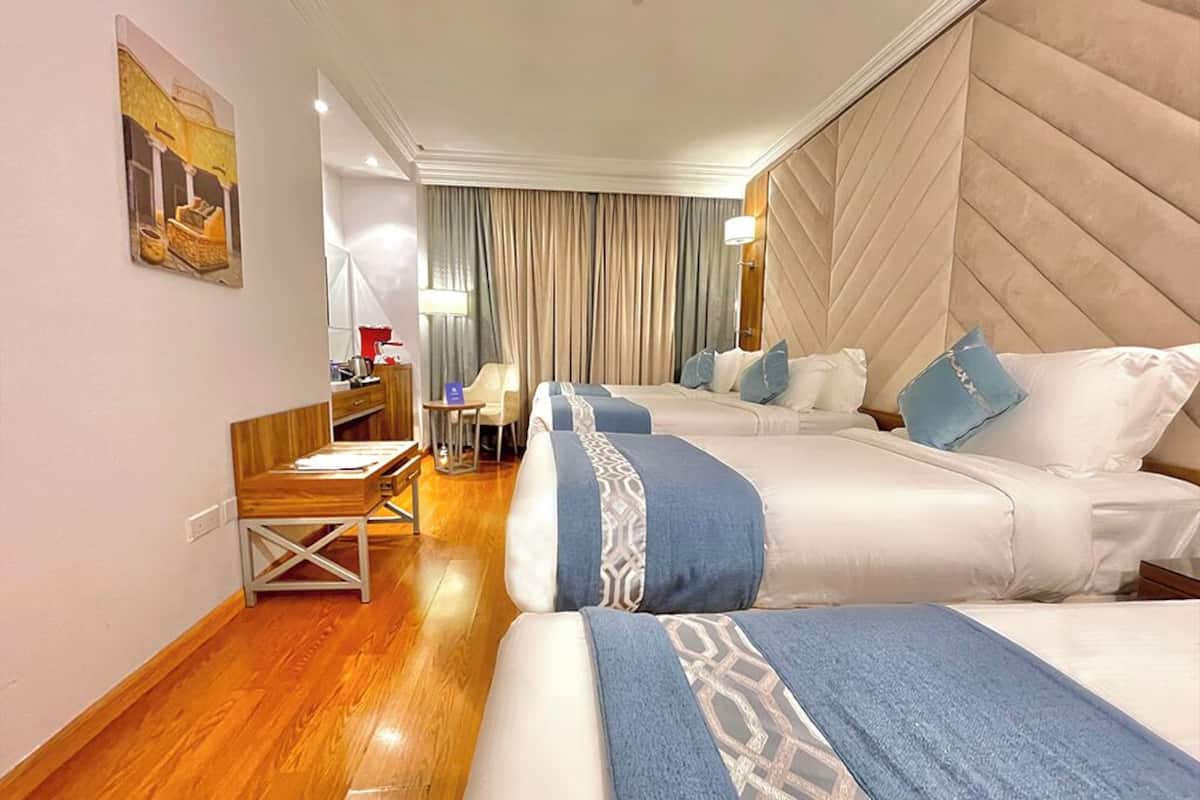 A hotel room with two beds, a desk, and a chair.