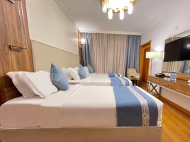 Habitación de hotel con dos camas, un escritorio, una silla, un televisor y un espejo.