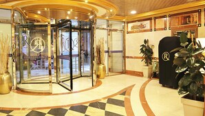A lobby with a checkered floor, a revolving door, and a reception desk with a logo. - ALRITZ ALMADINAH HOTEL - فندق الريتز المدينة (Madinah)