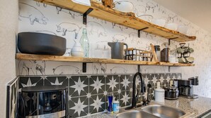 A kitchen with a granite countertop, stainless steel sink, and a coffee maker. - Downtown Trailside Cottage (Bentonville)