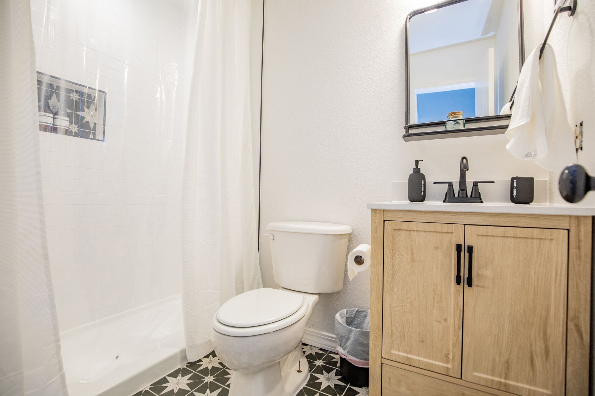 Ein Badezimmer mit Toilette, Duschvorhang, Waschbecken mit Spiegel und einem Schrank.